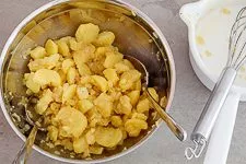 Kartoffelsalat in der Schüssel vermengen