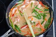 Die Kokosmilch-Sauce mit Gemüse und Garnelen zubereiten.