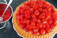 Tortenguss auf dem Erdbeerkuchen mit Mascarpone-Creme verteilen