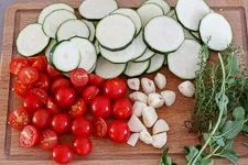 Zucchini, Kirschtomaten, Knoblauch und Kräuter runden Ofengemüse ab