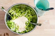 Caesar Salad mit Dressing vermengen