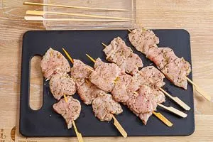 Souvlaki-Fleischscheiben auf eingeweichte Holzspieße aufspießen