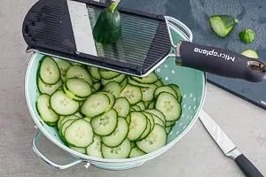 Frische Gurken in ein Sieb hobeln