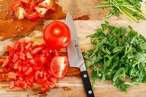 Tomaten und Rucola für den Nudelsalat klein schneiden