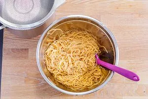 Nasse Spaghetti in einer Schüssel mit dem Dressing vermischt