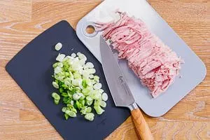 In Streifen geschnittener Kochschinken und in Ringe geschnittene Frühlingszwiebeln für Spaghettisalat