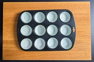 Muffinblech mit Papierförmchen füllen