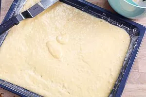 Rührteig für den Apfelkuchen auf das Blech streichen