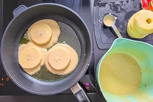 Teig und Apfelscheiben in der Pfanne portionieren