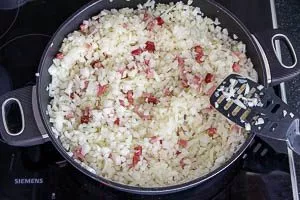 Zwiebeln und Speck in der Pfanne dünsten