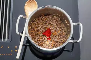 Tomatenmark zur Bolognese-Mischung hinzugeben