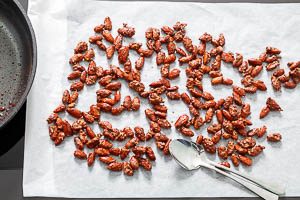 Breite die gebrannten Mandeln noch warm auf Backpapier aus, damit sie nicht aneinander kleben