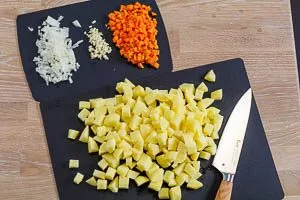 Kartoffeln, Möhre, Zwiebel und Knoblauch würfeln
