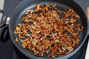 Röstzwiebeln als Topping für die Käsespätzle in der Pfanne anbraten