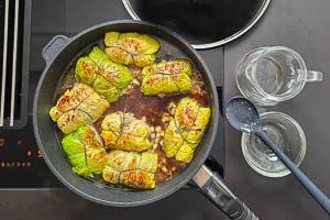 Zwiebeln und Speck mit in die Pfanne geben und Fond dazugießen. Für 30 Minuten schmoren lassen.