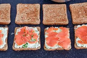 Die Avocado-Creme auf den Toast verteilen und den Räucherlachs verteilen