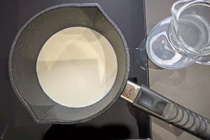 Milch in den Topf geben.
