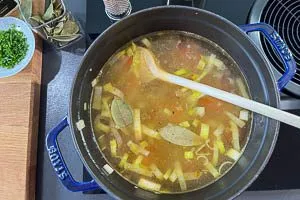 Mit Brühe ablöschen und Lorbeerblätter hinzugeben.