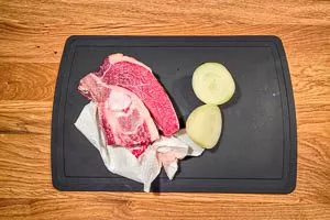 Suppenfleisch abwaschen und Zwiebel einmal durchschneiden.