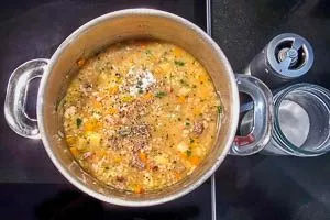 Petersilie und Suppenfleisch zur Suppe geben.