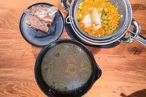 Fleisch entnehmen und Brühe in eine Schüssel gießen.