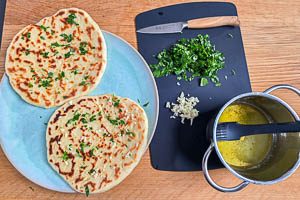 Für Garlic Naan Brote mit Butter und Knoblauch besteichen und mit Petersilie bestreuen