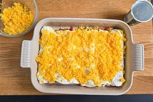 Enchiladas mit Schmand und Käse füllen.