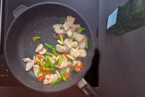 Gemüse und Hähnchenbrustfilet in Streifen in einer Pfanne anbraten
