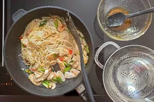 Reisnudeln in die Pfanne geben und mit Pad-Thai-Sauce ablöschen