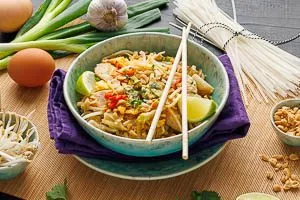 Pad Thai mit Koriander, gehackten Erdnüssen und Limette garnieren und in einer Schale servieren