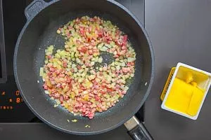 Butterschmalz in der Pfanne erhitzen und Zwiebeln und Speck anbraten