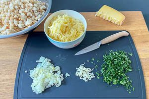 Weizenbrötchen vorbereiten, Zwiebel, Knoblauchzehe und Petersilie klein schnippeln und Bergkäse grob reiben.