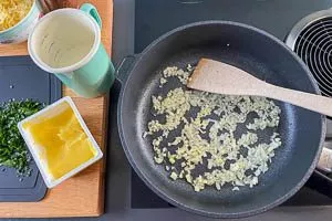 Zwiebel und Knoblauch in Butterschmalz anbraten. Milch zugie&szlig;en.