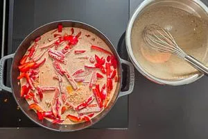 Paprikastreifen und Hähnchenbrustfilets in der Pfanne mit der Soßenmischung übergießen und in den Backofen stellen.