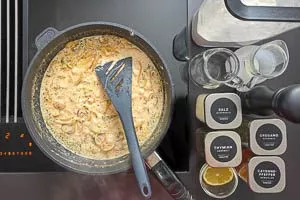 Mit Mehl bestreuen, mit Sahne und Geflügelfond ablöschen und mit Gewürzen abschmecken.