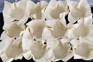 In jedes Förmchen ein Stück Blätterteig geben.