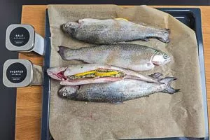 Forellen auf einem Backblech mit Backpapier auslegen, würzen und befüllen