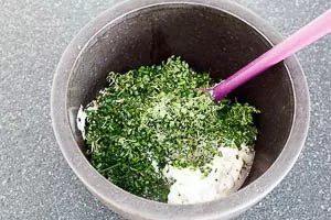 Kräuter mit dem Quark in einer Schüssel vermengen