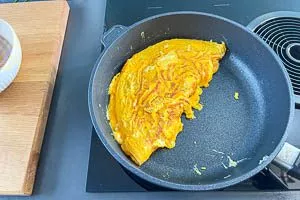 Eine Omeletthälfte über die andere schlagen und auf einen Teller geben.
