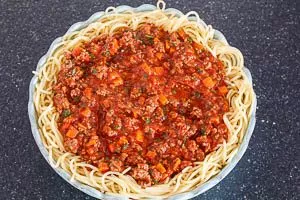 Hackfleisch-Soße auf die Spaghetti geben