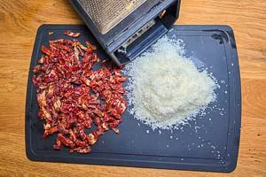Getrocknete Snacktomaten schneiden und Parmesan reiben