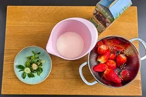 Erdbeeren waschen und vorbereiten, Milch in Rührbecher geben.