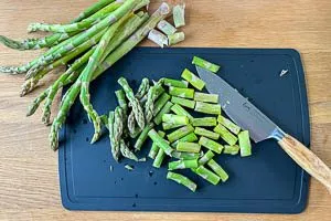 Holzige Enden vom rohen grünen Spargel abschneiden
