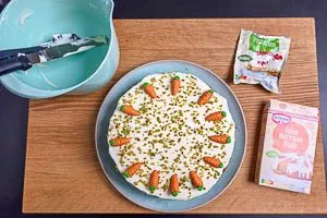 Kuchen mit Marzipankarotten und Pistazien dekorieren.