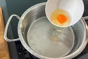 Ei aus der Tasse ins Wasser gleiten lassen.