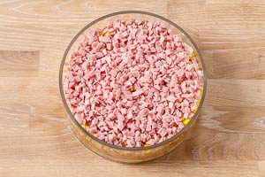 Schichtsalat-Zutaten in eine Glasschüssel schichten