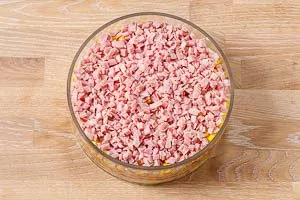Schichtsalat-Zutaten in eine Glasschüssel schichten