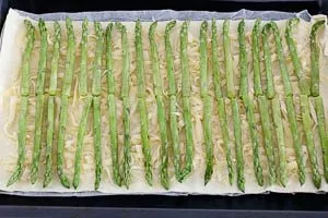 Grünspargel auf dem Blätterteig mit Käse verteilen