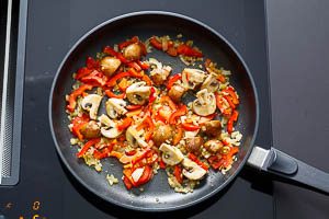 Paprika, Champignons, Zwiebel und Knoblauch in der Pfanne anbraten