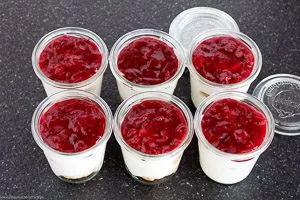 Creme auf die Windbeutel verteilen und Grütze darauf schichten.